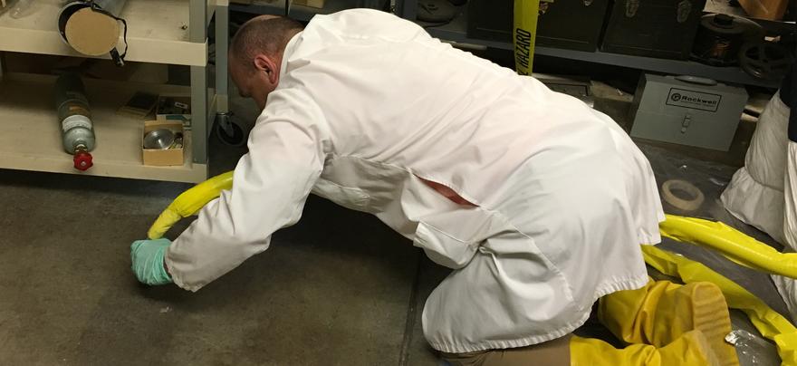 Man in lab coat cleaning up a spill.